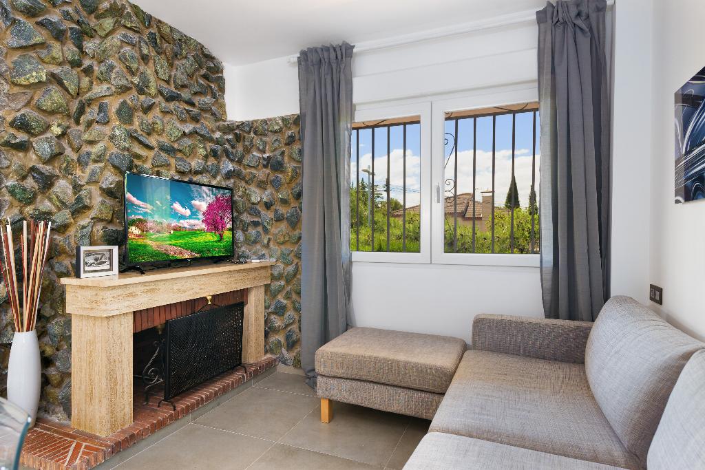 Salón con pared de piedra, televisor y sofá