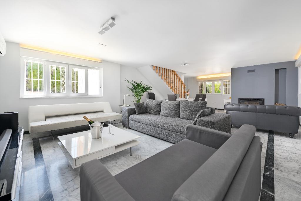 Salón con sofás, chimenea y ventanas al jardín
